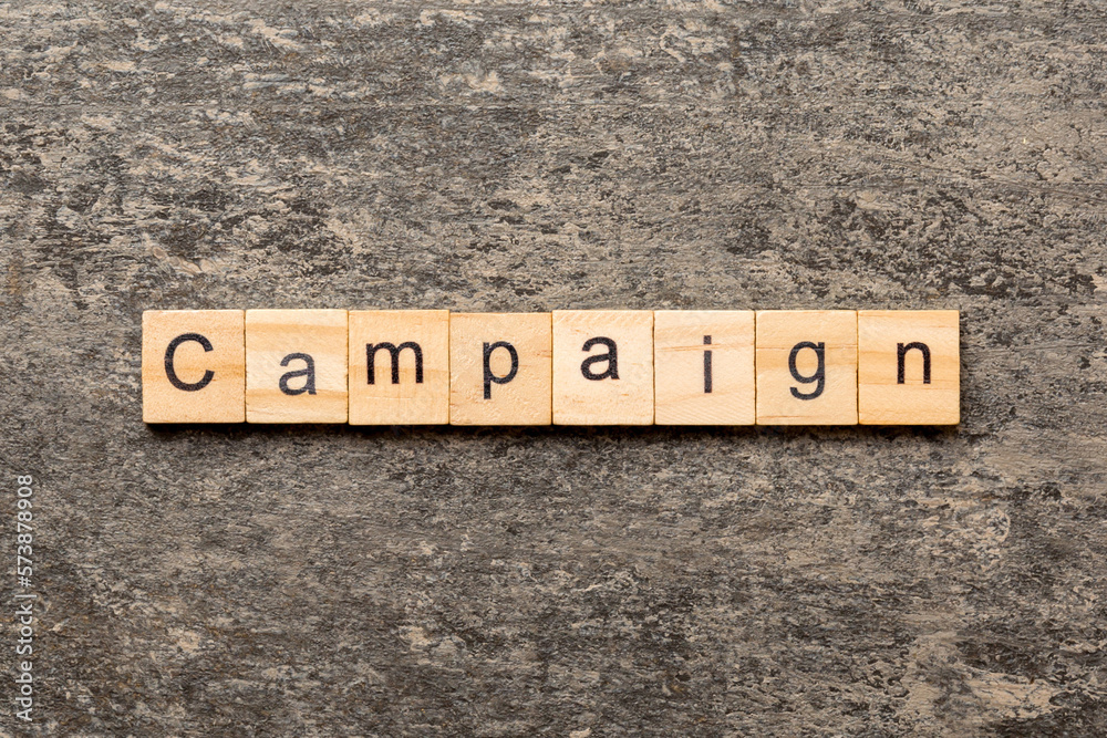 Fototapeta premium CAMPAIGN word written on wood block. CAMPAIGN text on table for your desing, concept