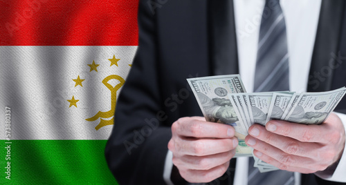 Hands holding dollar money on flag of Tajikistan