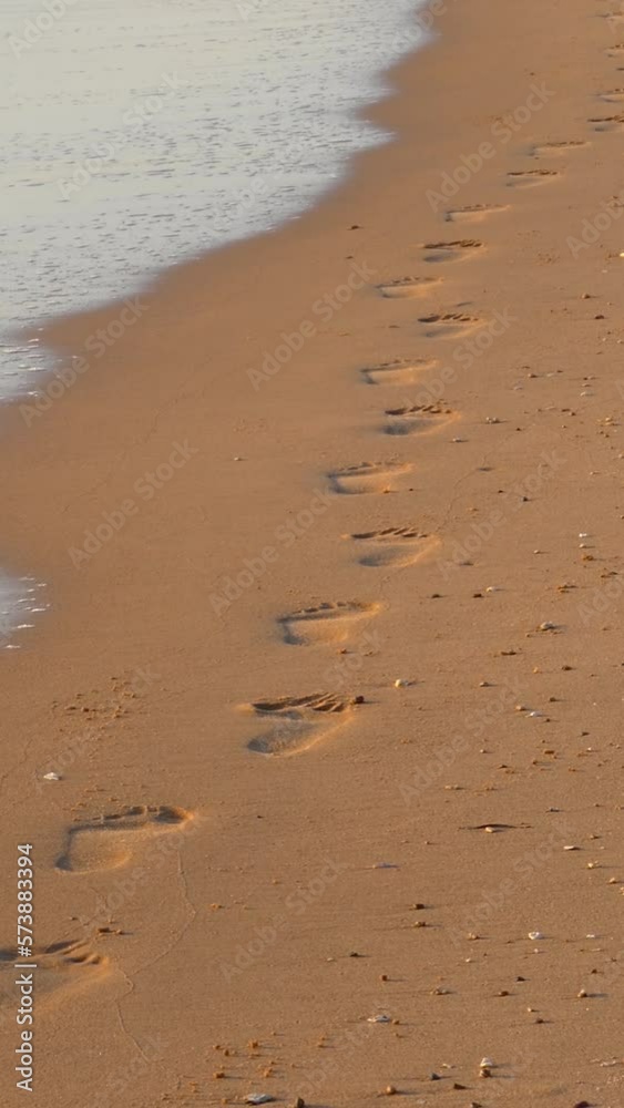 Footprints on sand beach along the edge of sea. Vertical video Footprints on sand beach along the edge of sea. Vertical video