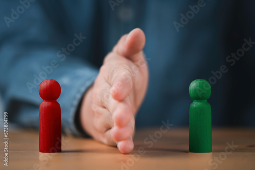Palm hand blocking and divide between red and green wooden figure for resolving conflict and mediate management concept. photo