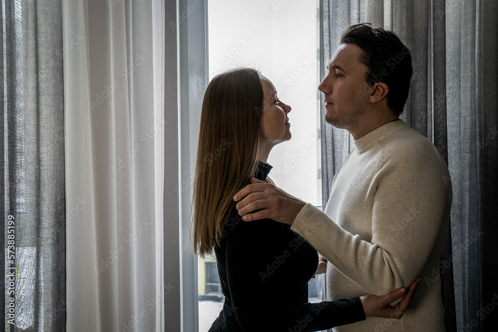 romantic couple hugging each other near window at home, woman in black man in white, yin yang contrast, opposites attract. Love my second half romantic couple hugging each other near window at home, woman in black man in white, yin yang contrast, opposites attract. Love my second half