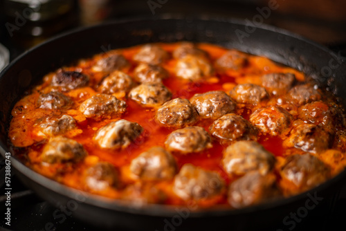 Cooking homemade meatballs in a frying pan in a sauce of tomatoes and sour cream.
