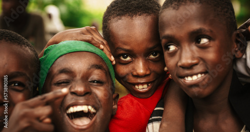Close Up Of the Faces of a Group of Rural African Young Boys Smiling, Laughing and Posing for Camera. A Group of Expressive Black Male Friends Enjoying Their Childhood and Joking Around Together © Kitreel
