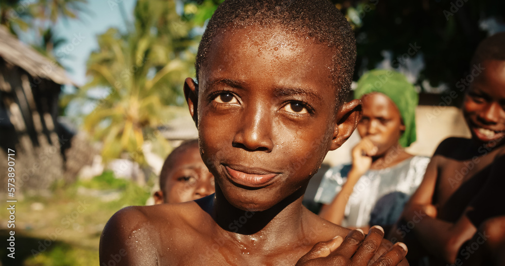 Close Up Portrait of a Playful Authentic African Kid Looking at the Camera and Laughing with Other Kids in the Background. Happy Energetic Black Boy Sharing his Beautiful Big Smile with the World Close Up Portrait of a Playful Authentic African Kid Looking at the Camera and Laughing with Other Kids in the Background. Happy Energetic Black Boy Sharing his Beautiful Big Smile with the World
