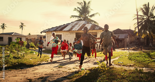 Group of African Little Children Running Towards the Camera and Laughing in Rural Village. Black Kids Full of Life and Joy Enjoying their Childhood and Playing Together. Little Faces with Big Smiles photo