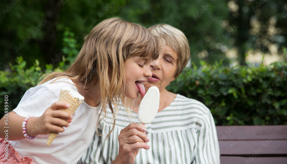 grandmother and child granddaughter eat ice cream in the park on a summer day. happy family has fun together in nature grandmother and child granddaughter eat ice cream in the park on a summer day. happy family has fun together in nature
