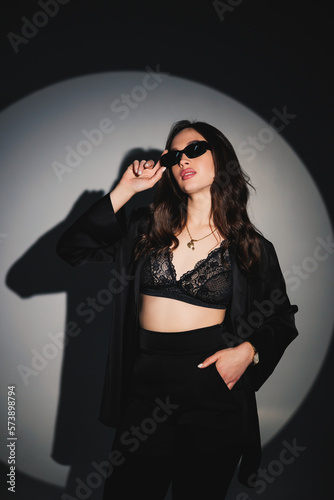 Young elegant stylish woman in a black suit. Studio shot. A woman in a black suit and black glasses on a white background © Дмитрий Ткачук