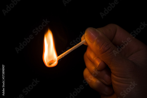 A burning match in hand. Hand with a burning match in the dark. 