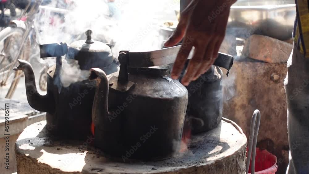 Tea is boiled in two burning aluminum kettles in a clay oven. urbanized everyday scene. Slow-motion video. Tea is boiled in two burning aluminum kettles in a clay oven. urbanized everyday scene. Slow-motion video.