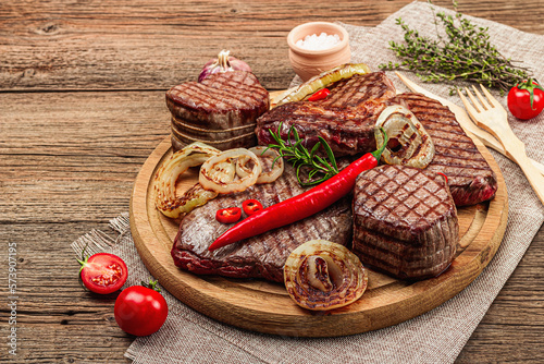 Grilled set of various steaks with vegetables. Ribeye, eye round, flank and striploin steaks