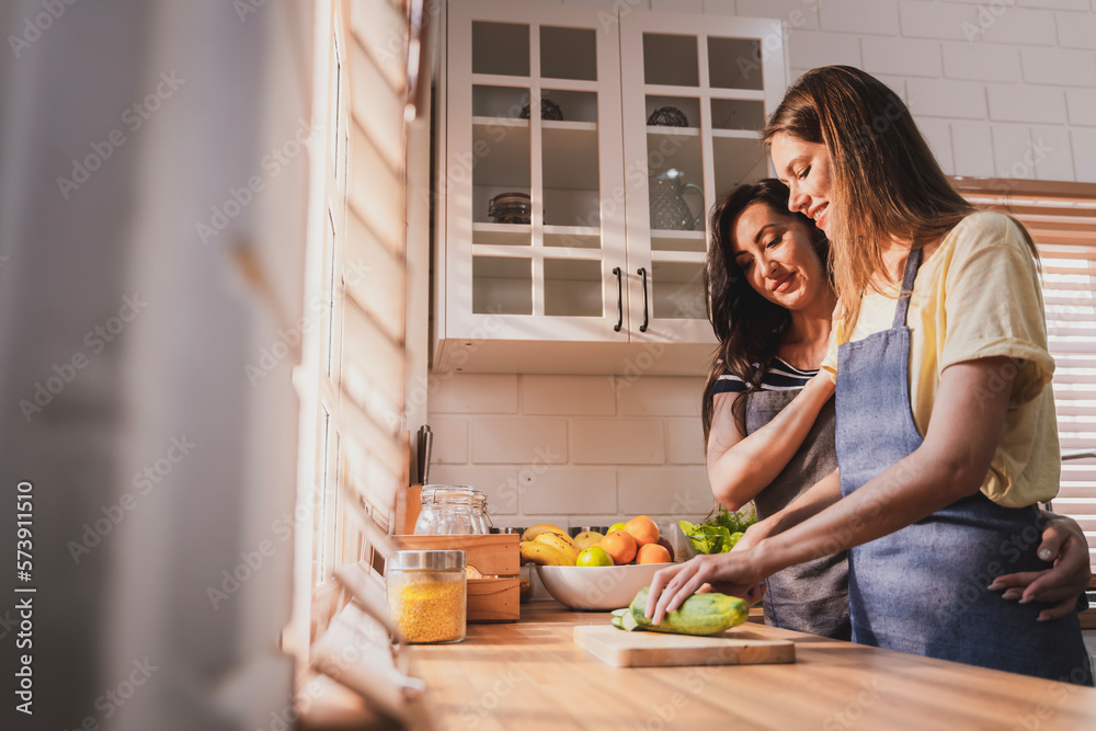 Female and female or LGBT couples are happily cooking bread together in the home kitchen.
