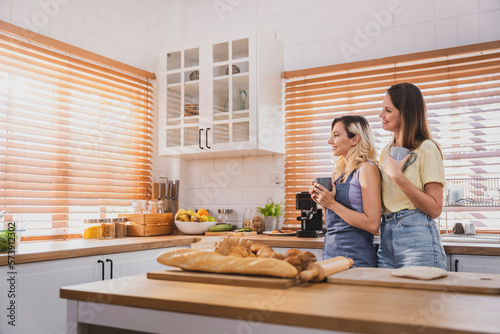 Female and female or LGBT couples are happily cooking bread together in the home kitchen.