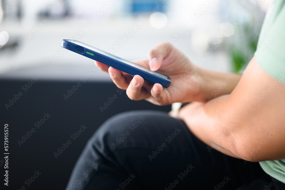 Closeup hand of a woman holding a smart phone while sitting in the coffee shop, woman text the message on the screen
