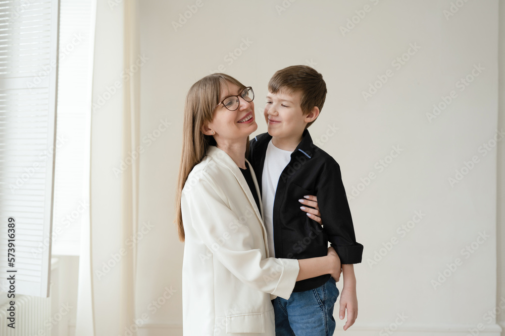 Happy mom with glasses and preschool-age son hugging and smiling on a white background Happy mom with glasses and preschool-age son hugging and smiling on a white background