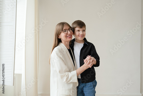 Happy mom with glasses and preschool-age son hugging and smiling on a white background