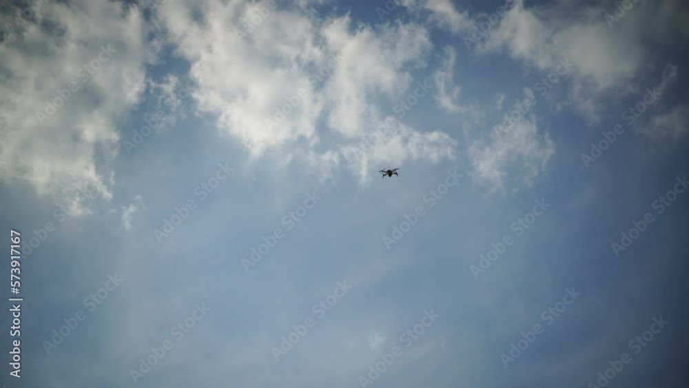 Hovering drone flying upward on a cloudy sky backdrop Hovering drone flying upward on a cloudy sky backdrop