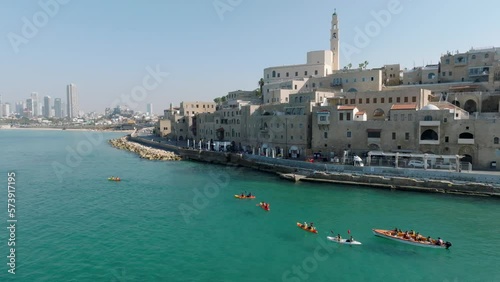 Aerial footage of a group of children paddling kayaks at the exit of the beautiful old port of Jaffa