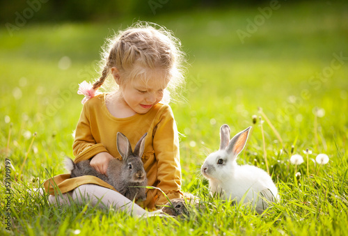 the girl  on the sunny lawn among the rabbits