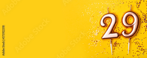 29 years celebration. Greeting banner. Gold candles in the form of number twenty nine on yellow background with confetti. photo