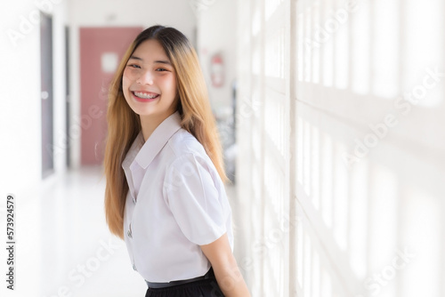 Portrait of cute Thai student in university student uniform. Young Asian beautiful girl standing smiling confidently at university.