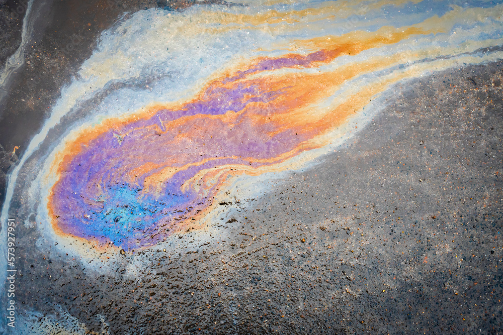 Obraz premium Close-up of an iridescent oil or gasoline spill on a wet asphalt, viewed from above.