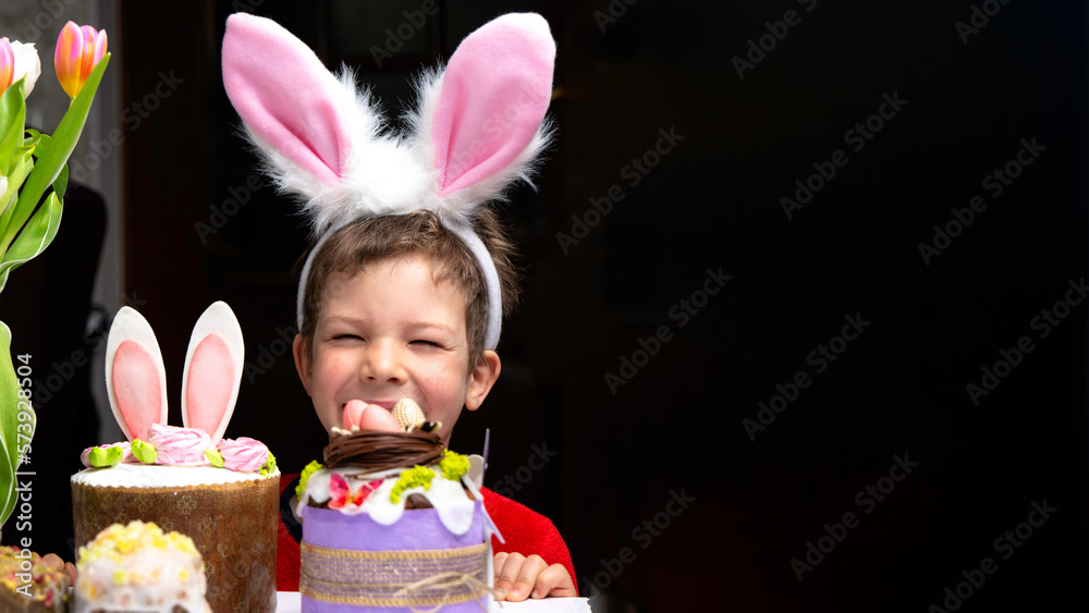 Cute little boy with bunny ears looking at tasty easter sweet cake