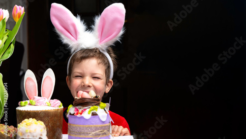 Obraz na płótnie Cute little boy with bunny ears looking at tasty easter sweet cake w salonie