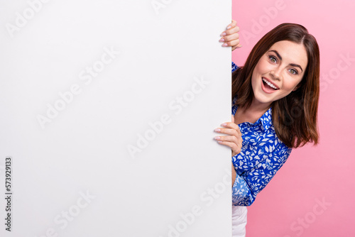 Closeup photo of young overjoyed woman excited hiding big paper placard poster empty space proposition new brand isolated on pink color background