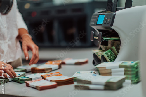 Bank employees using money counting machine while sorting and counting paper banknotes inside bank vault. Large amounts of money in the bank © .shock
