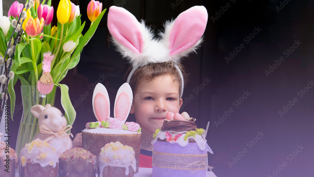 Cute little boy with bunny ears looking at tasty easter sweet cake