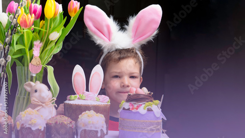 Obraz na płótnie Cute little boy with bunny ears looking at tasty easter sweet cake w salonie
