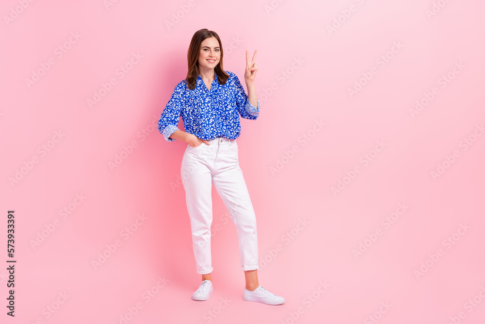 Full length photo of friendly sweet woman dressed blue blouse showing v-sign empty space isolated pink color background Full length photo of friendly sweet woman dressed blue blouse showing v-sign empty space isolated pink color background