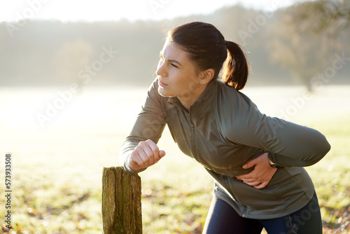 Young woman exercising on a sunny winter morning has pain and side stitch from training and running