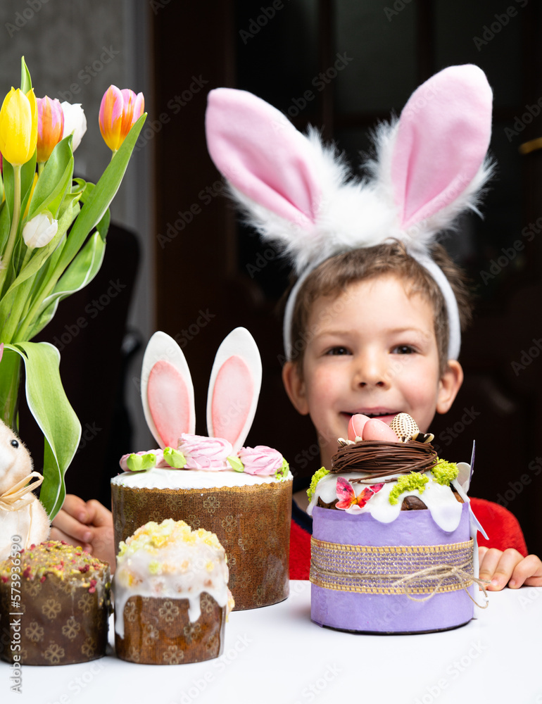 Cute little boy with bunny ears looking at tasty easter sweet cake