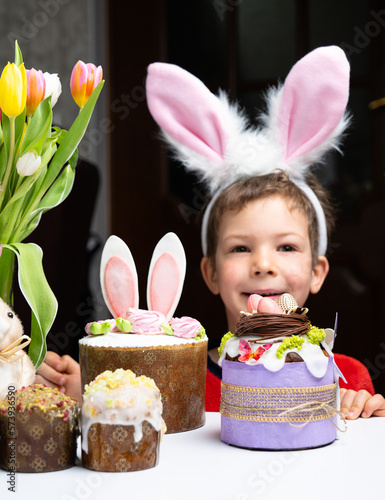 Obraz na płótnie Cute little boy with bunny ears looking at tasty easter sweet cake w salonie