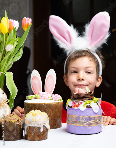Obraz na płótnie Cute little boy with bunny ears looking at tasty easter sweet cake w salonie