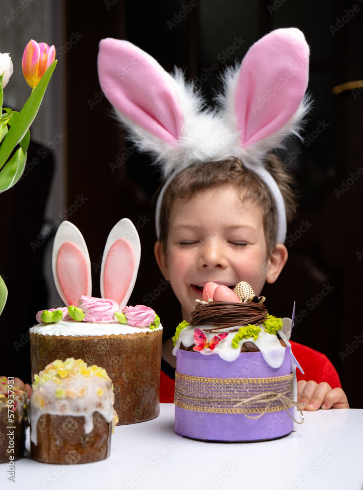 Cute little boy with bunny ears looking at tasty easter sweet cake