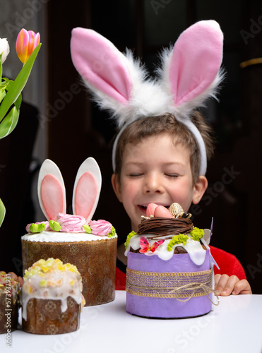 Obraz na płótnie Cute little boy with bunny ears looking at tasty easter sweet cake w salonie