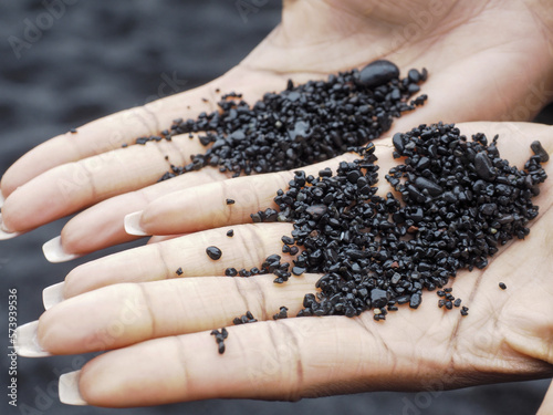 Two hands full of black sand and rocks
