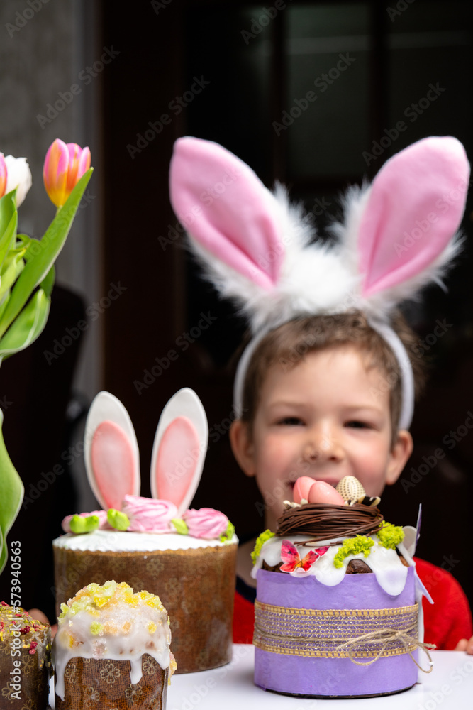 Cute little boy with bunny ears looking at tasty easter sweet cake