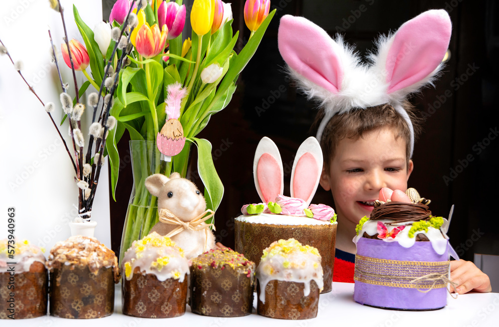 Cute little boy with bunny ears looking at tasty easter sweet cake