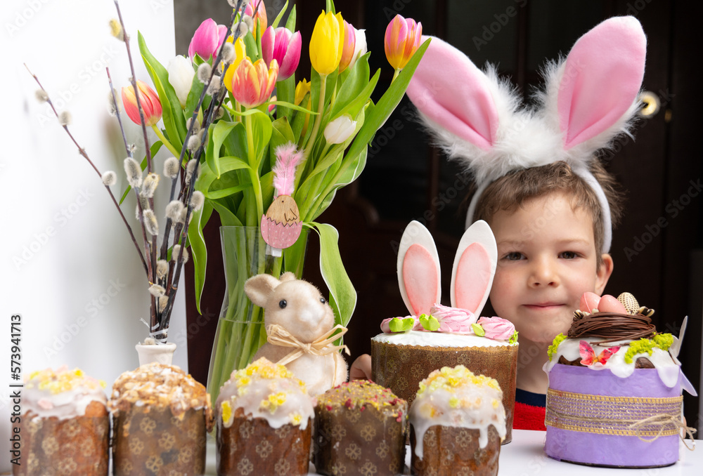Cute little boy with bunny ears looking at tasty easter sweet cake