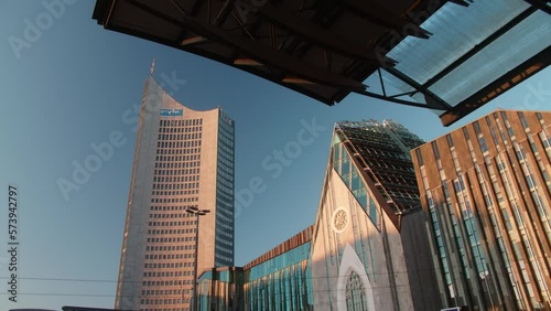 The outside of the university of Leipzig and a skyscraper in Saxony, Germany. The building is a transformed church and showcases modern architecture.  During sunrise golden hour.