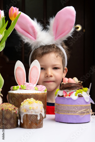 Obraz na płótnie Cute little boy with bunny ears looking at tasty easter sweet cake w salonie