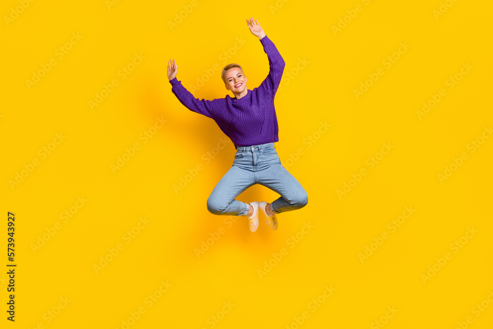 Full size portrait of cheerful overjoyed girl jumping raise hands have fun isolated on yellow color background