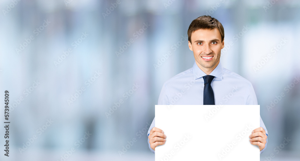 Portrait image of business man professional bank manager in confident cloth necktie holding showing empty white banner signboard paper poster with copy space area. Blurred office background Portrait image of business man professional bank manager in confident cloth necktie holding showing empty white banner signboard paper poster with copy space area. Blurred office background