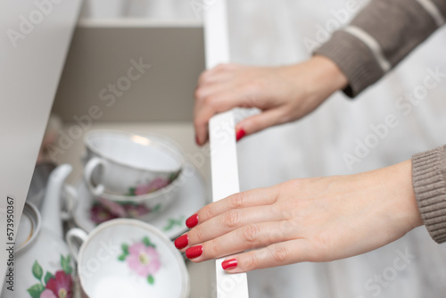 woman opens a drawer with dishes in the kitchen