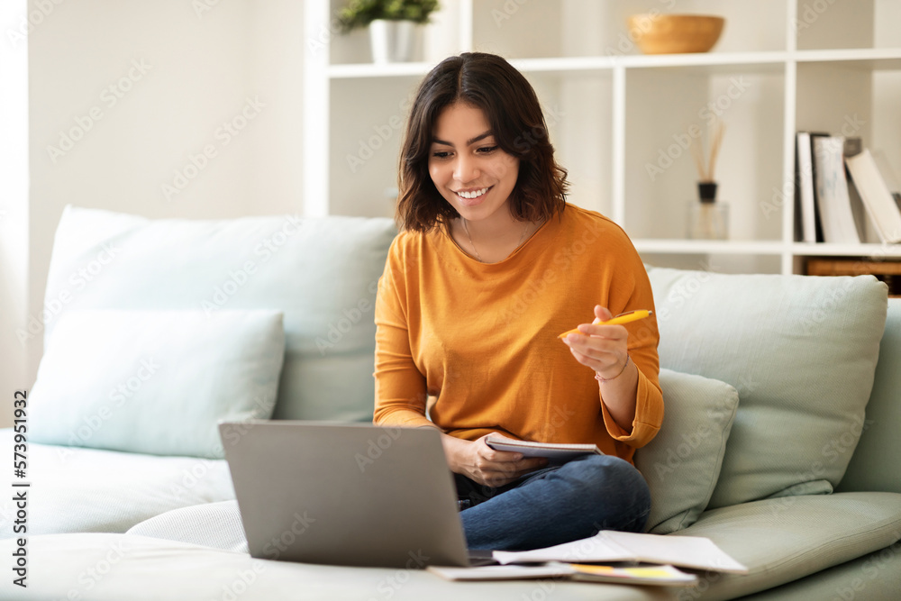 Smiling Arab Woman Watching Webinar On Laptop At Home And Taking Notes Smiling Arab Woman Watching Webinar On Laptop At Home And Taking Notes