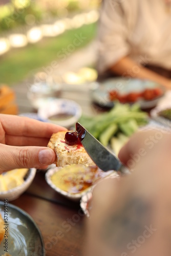 a person holding a knife and a piece of food in their hand and a bowl of food in the background