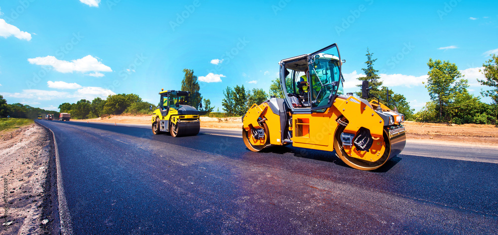 industrial landscape with rollers that rolls a new asphalt in the roadway. Repair, complicated transport movement.